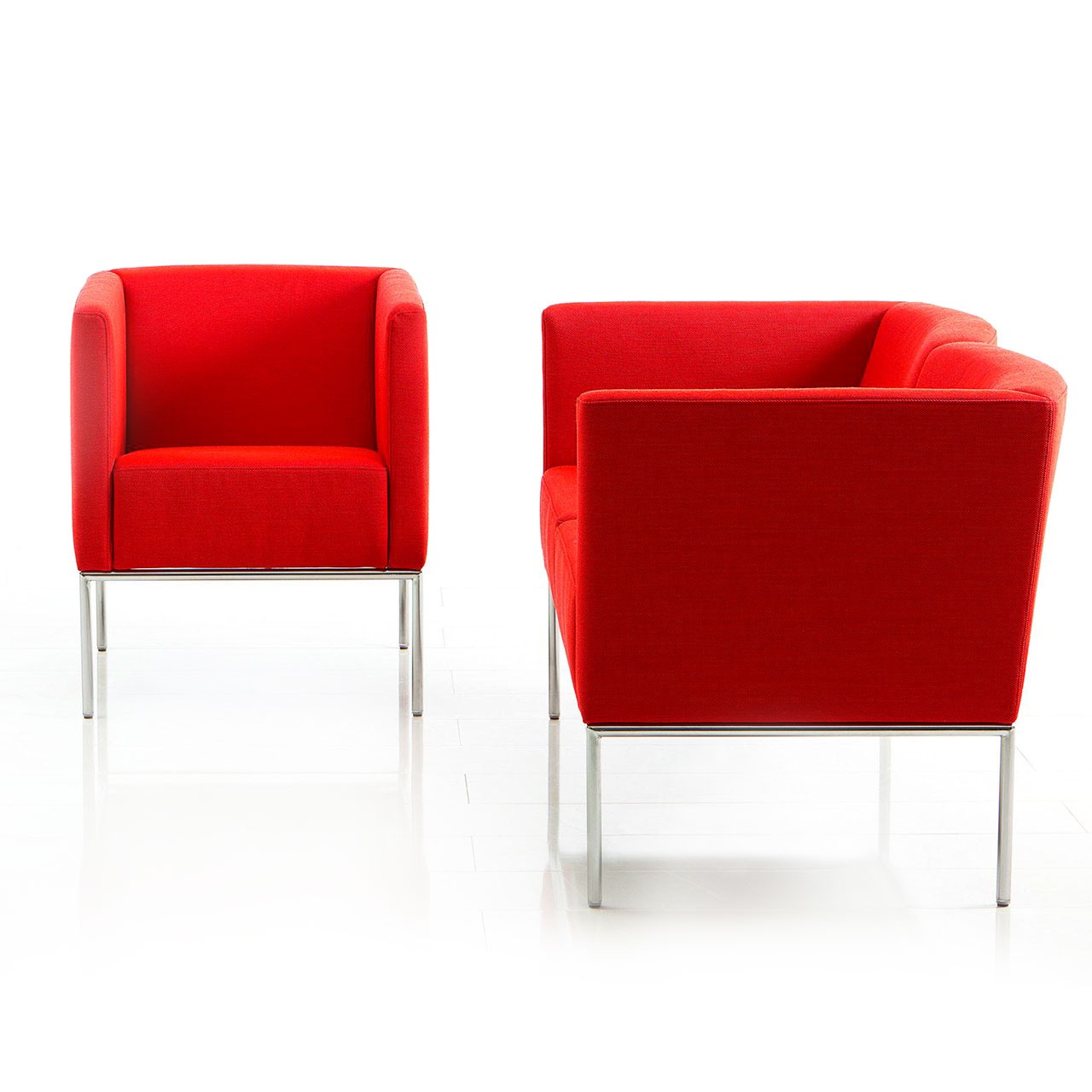 Zwei rote Sessel der Serie add1 stehen im rechten Winkel zueinander.