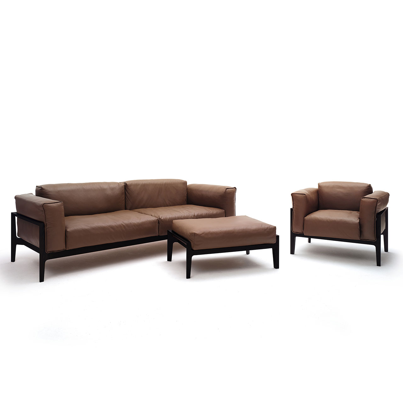 Ensemble bestehend aus Sofa, Hocker und Sessel mit gleichem braunem Lederbezug auf dunklem Holzgestell