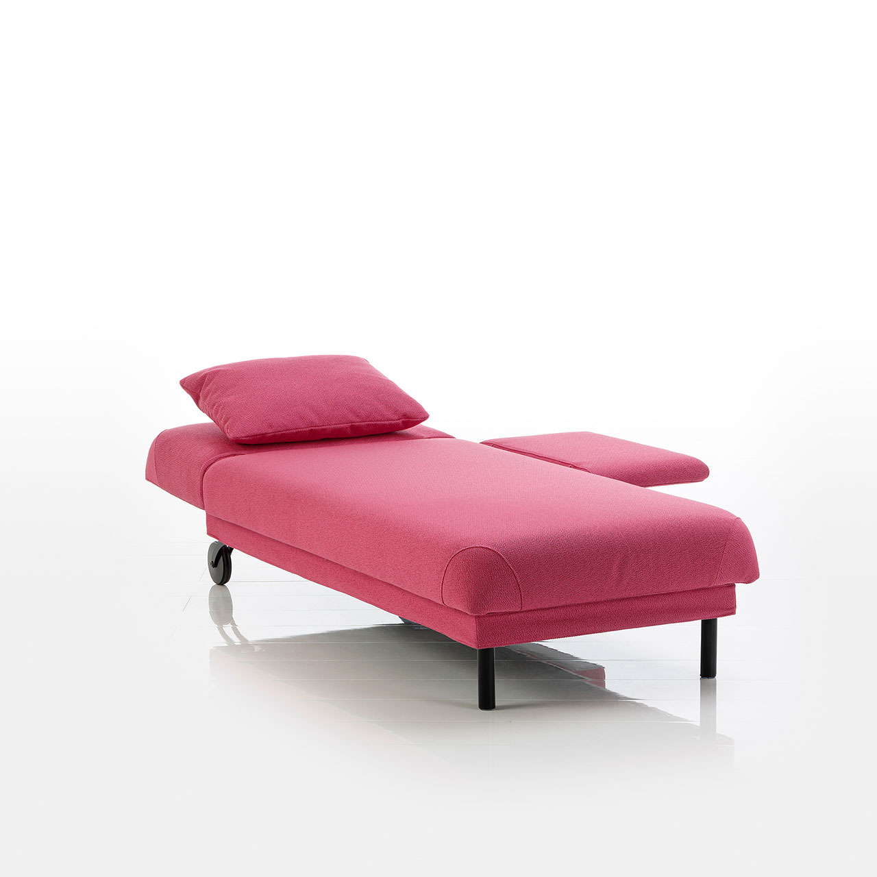 Recamiere in pinkem Stoff mit Rollen an der Kopfseite und zylindrischen Füßen an der Fußseite. Das Kopfteil ist höhenverstellbar. Kopfteil und Armlehne sind abgeklappt.
