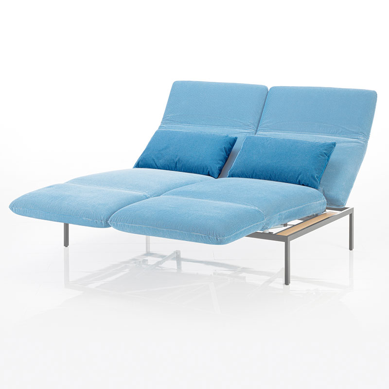 Sofa in hellblauem Stoff. Beide Sitze sind zur Relaxposition umgeschwenkt. Die Kissen wurden farblich hervorgehoben.