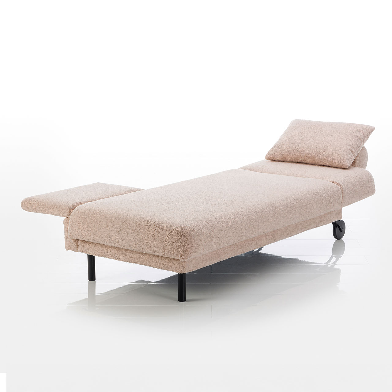 Recamiere in hellbraunem Stoff mit Rollen an der Kopfseite und zylindrischen Füßen an der Fußseite. Mit höhenverstellbarem Kopfteil und verschiebbarer Armlehne rechts.