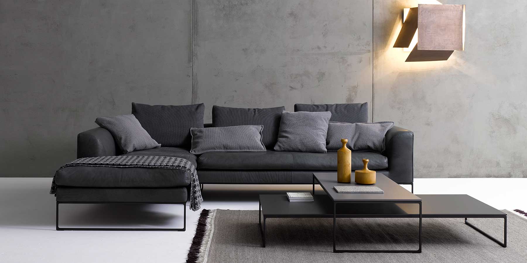 Graues Sofa mit schwarzen Kufen und vielen Kissen in Wohnzimmer