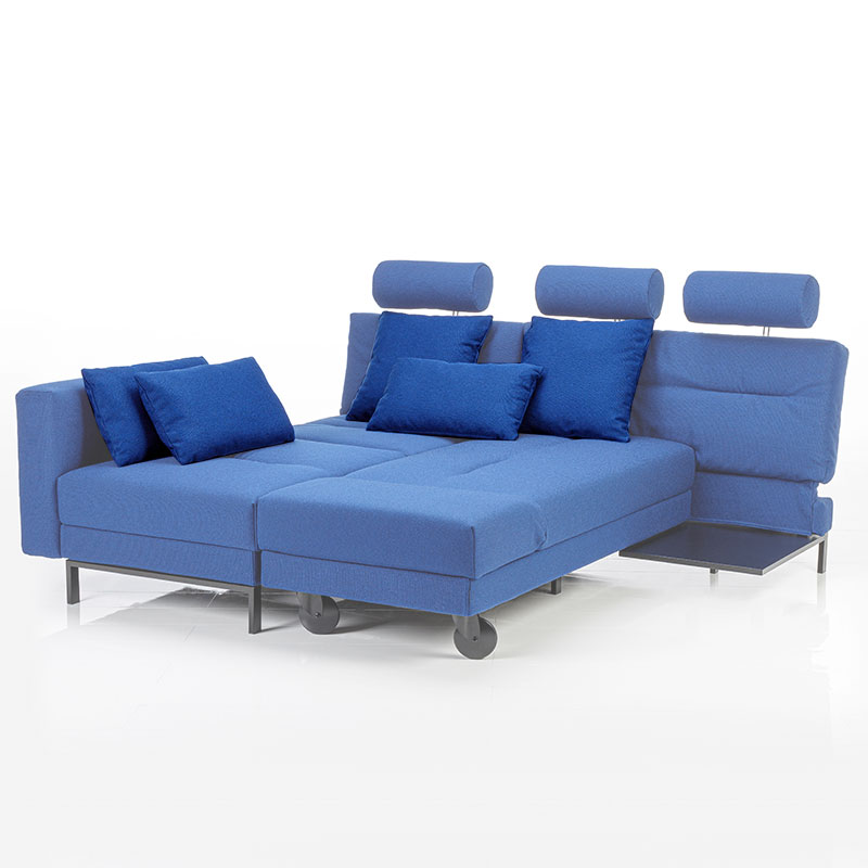 Blaue Eckgarnitur zum Doppelbett umgebaut. Die Kissen sind farblich hervorgehoben.