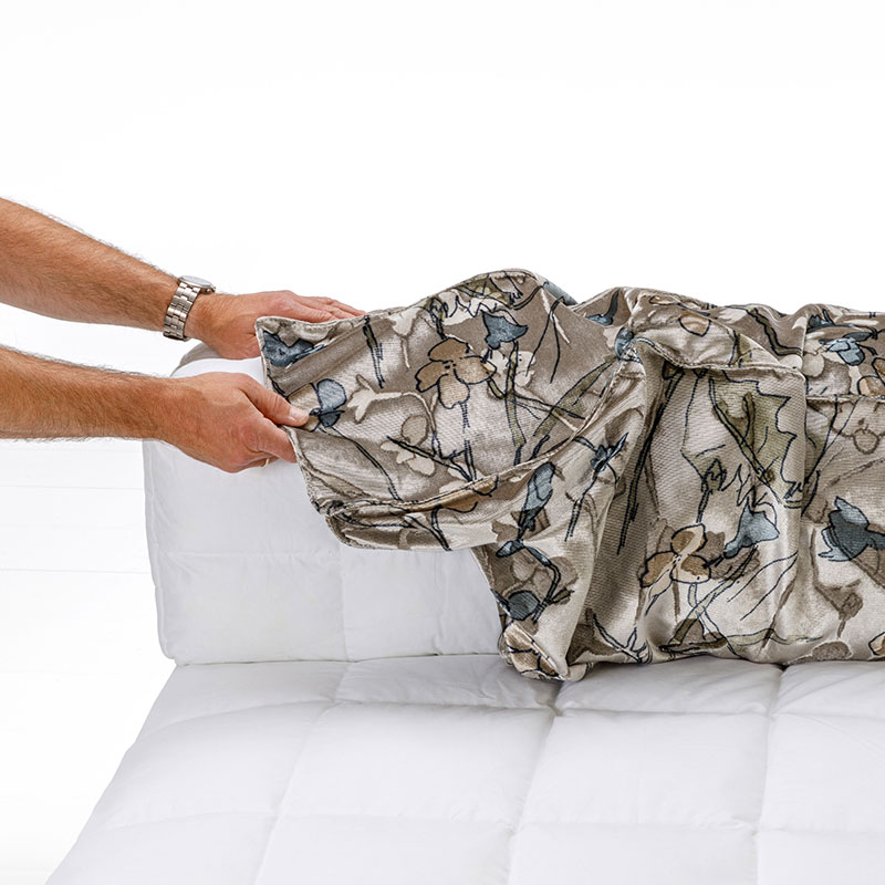 LZwei Hände beziehen einen Sofarücken mit einem gemusterten Stoffbezug.