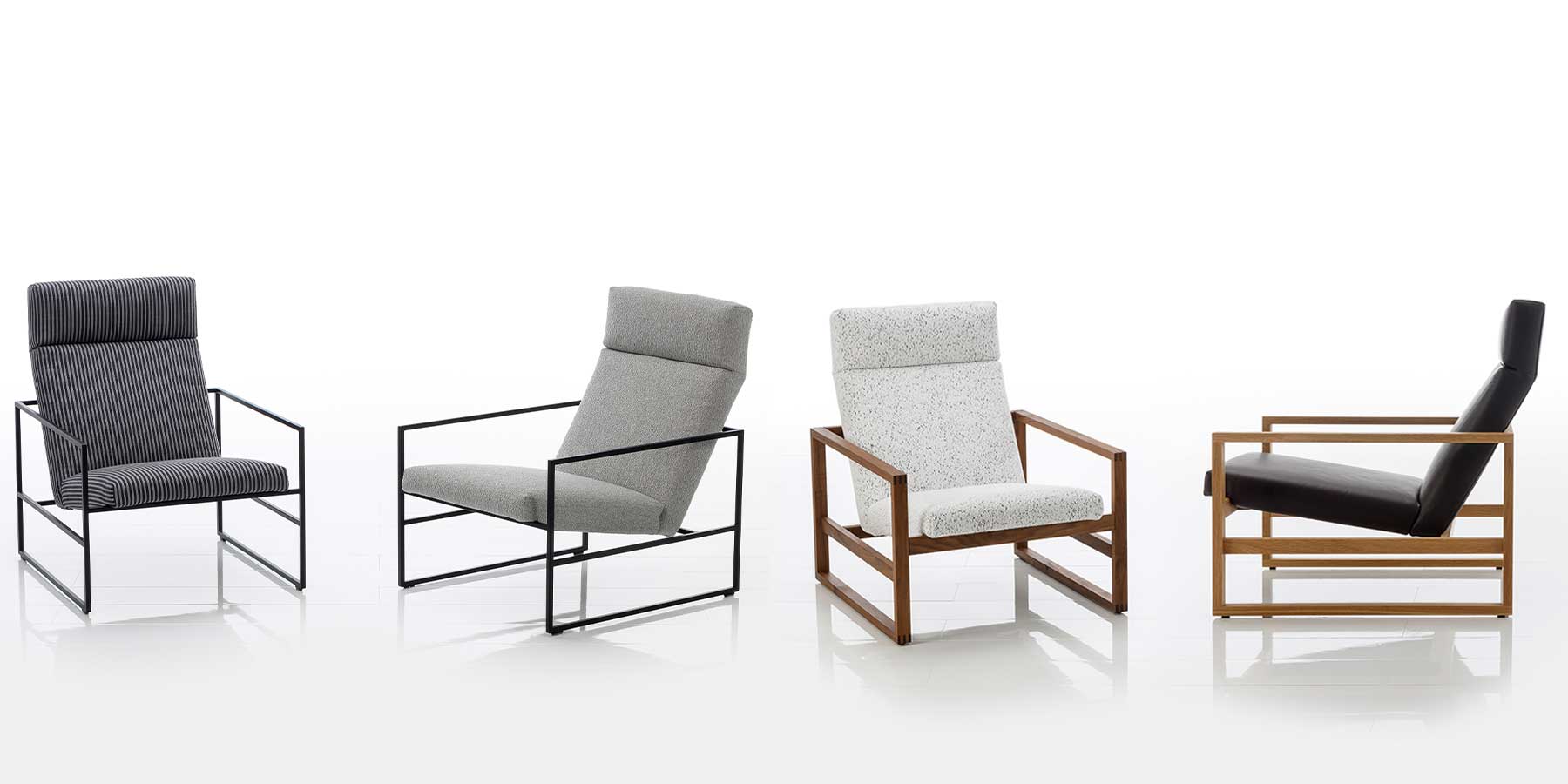 Vier Loungesessel der Serie grace von brühl. Die beiden linken Sessel haben ein Untergestell aus schwarzem Metall, die beiden rechten Sessel haben ein Gestell aus dunklem Holz. Die Sessel sind mit Stoff in grau, weiß und schwarz bezogen.