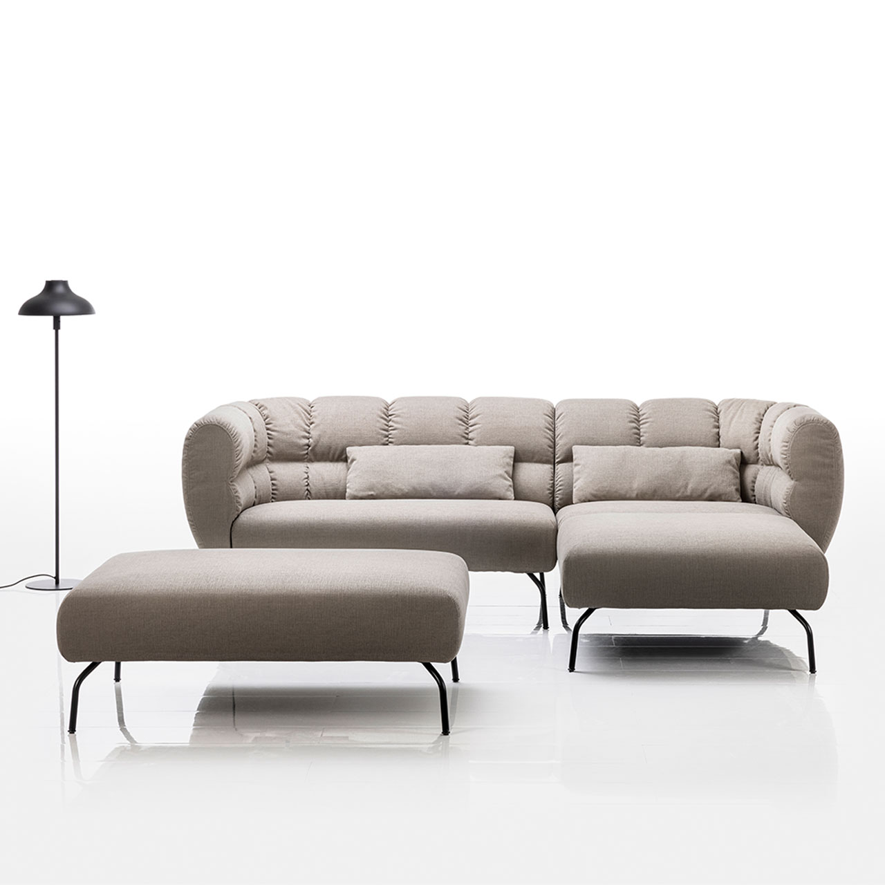 Ambientebild: Eckgarnitur von brühl magnolia mit Longchair rechts in grauem Leder mit schwarzen Füßen. Links vor der Garnitur steht eine Bank.