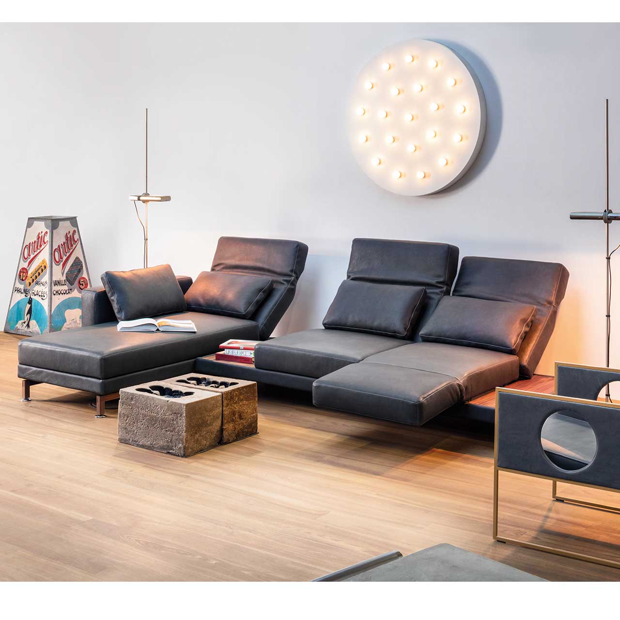 Eckgarnitur in schwarzem Leder mit Longchair links und mit Ablagefläche zwischen Longchair und Anstellsofa.