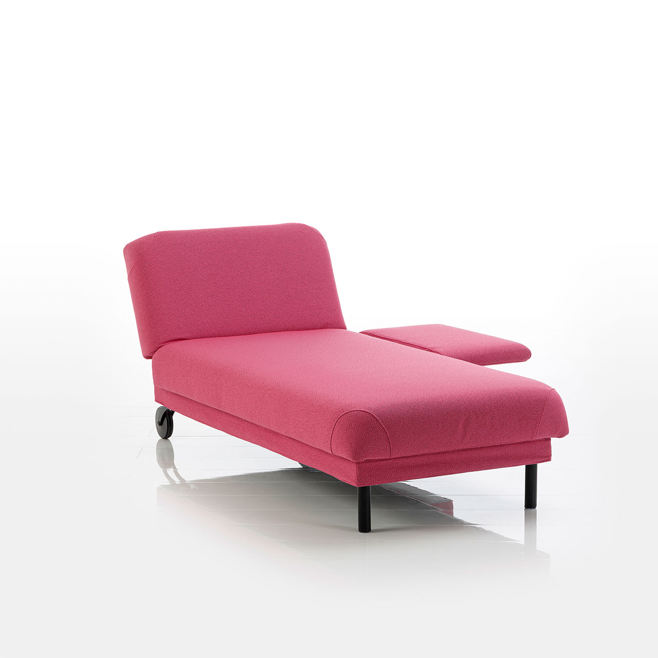 Recamiere in pinkem Stoff mit Rollen an der Kopfseite und zylindrischen Füßen an der Fußseite. Das Kopfteil ist höhenverstellbar. Die Armlehne rechts vom Kopfteil ist abgeklappt.