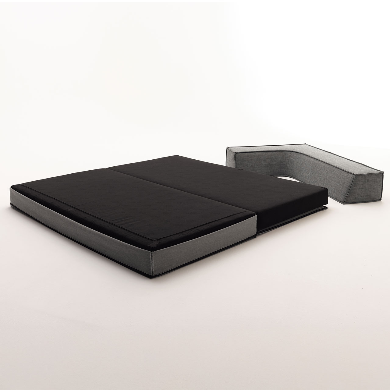 Das Schlafelement ist aufgeklappt, man sieht die schwarze Liegefläche. Das Rückenelement liegt daneben.