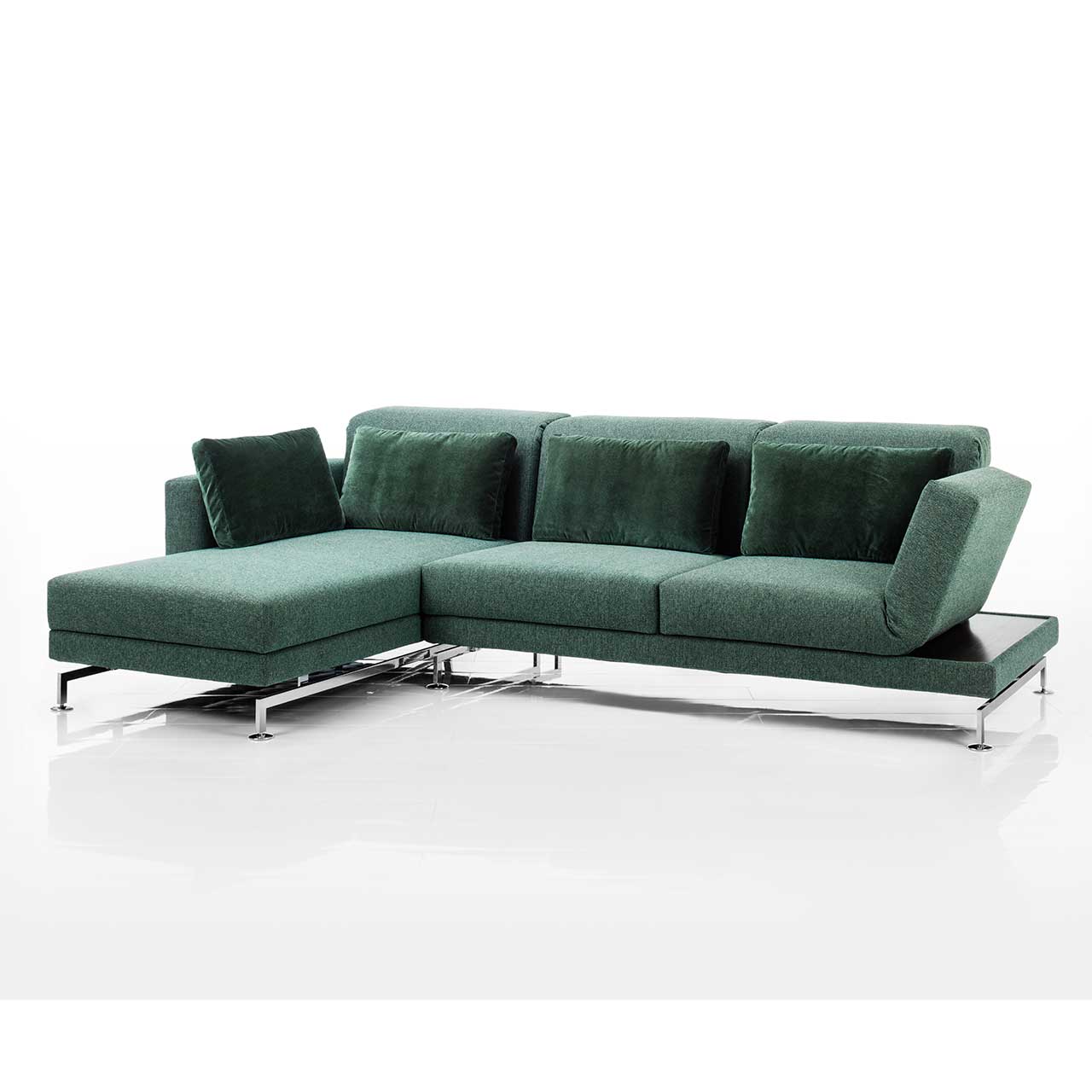 Eckgarnitur mit Longchair links in grünem Stoff. Rechts neben der Armlehne befindet sich eine Ablagefläche in dunklem Holz.