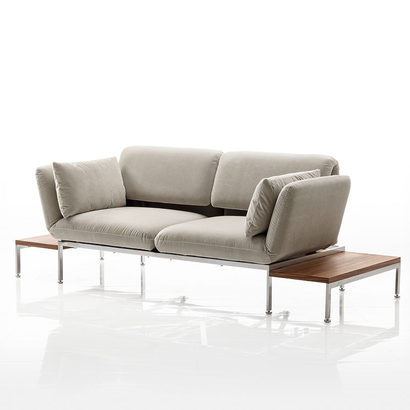 Sofa in hellem Stoff. Rechts und links ist je ein kleiner Tisch angehängt. 