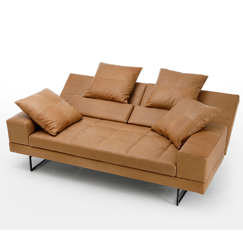 Ein opulentes, caramelfarbenes Ledersofa. Die Rückenlehnen sind abgesenkt. Die SItzfläche ist gesteppt.