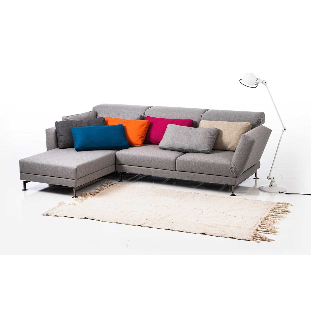 Eckgarnitur in grauem Stoff mit Longchair links, dekoriert mit sieben Kissen.