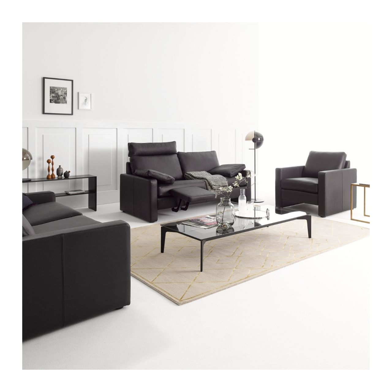 Zwei Sofas und ein Sessel der Serie COR Conseta in dunkelbraunem Leder mit Wangenarmlehnen. Die Möbel stehen als Sitzlandschaft arrangiert um einen gläsernen Tisch.