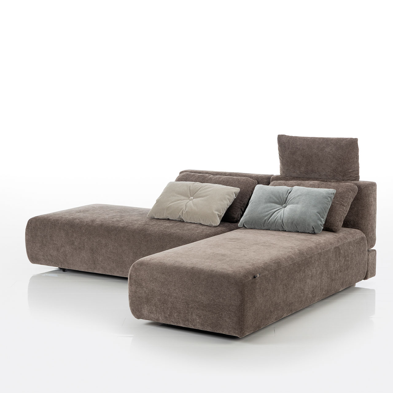 Bodennahes braunes Eckofa mit Drehsofa links und Longchair rechts. Auf dem Sofa liegen zwei eckige Kissen.