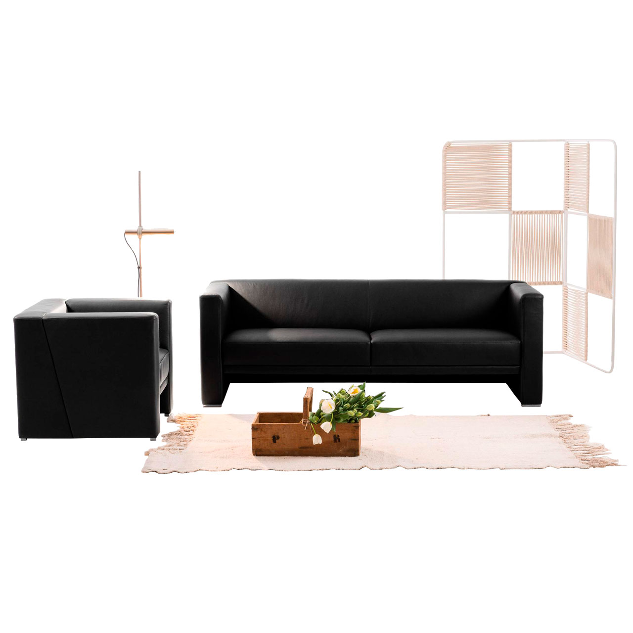 Schwarzes Ledersofa. Links daneben steht ein schwarzer Ledersessel.
