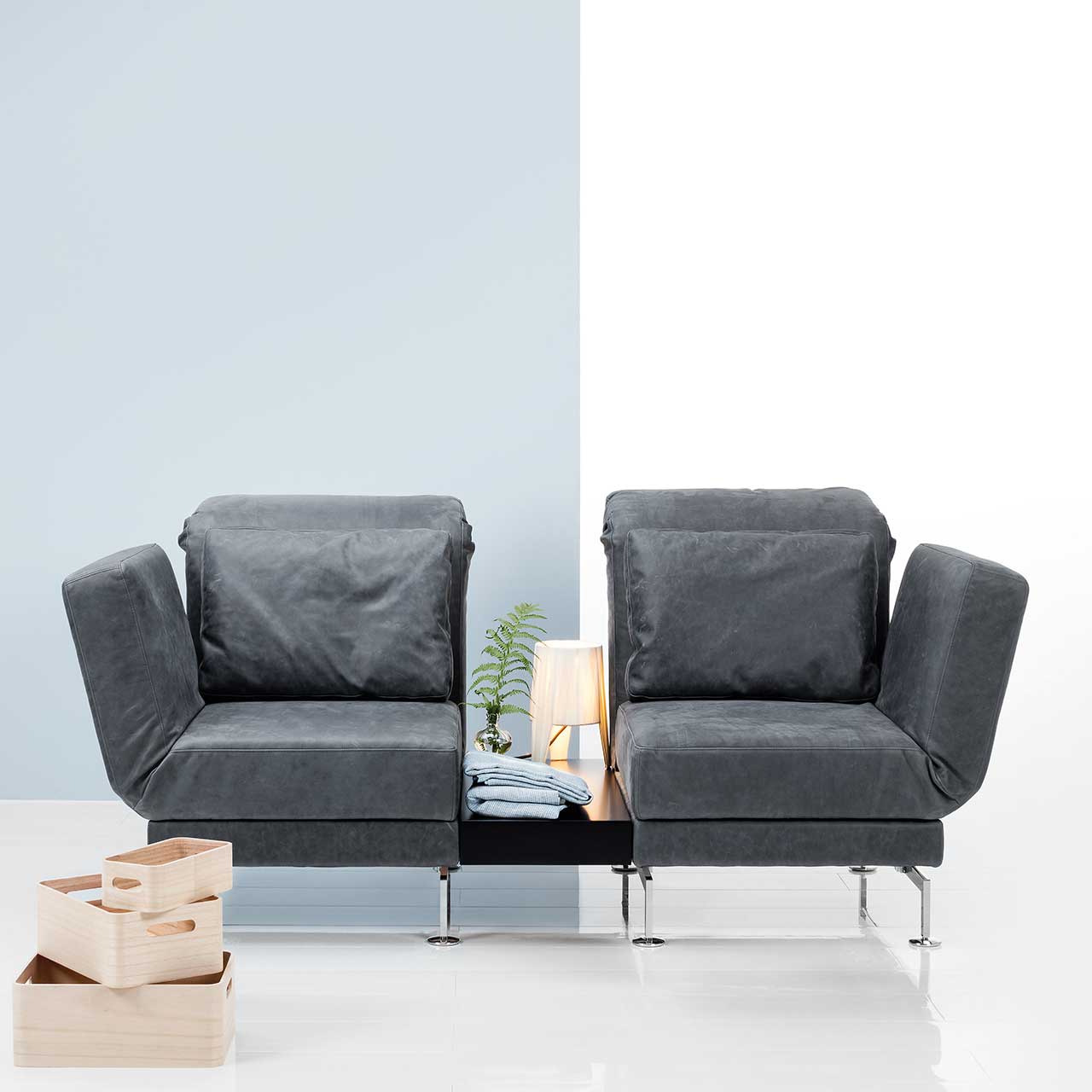 Zwei Relaxsessel der Serie brühl moule in grauem Leder sind mit einem Einhängetisch zu einer Garnitur verbunden.