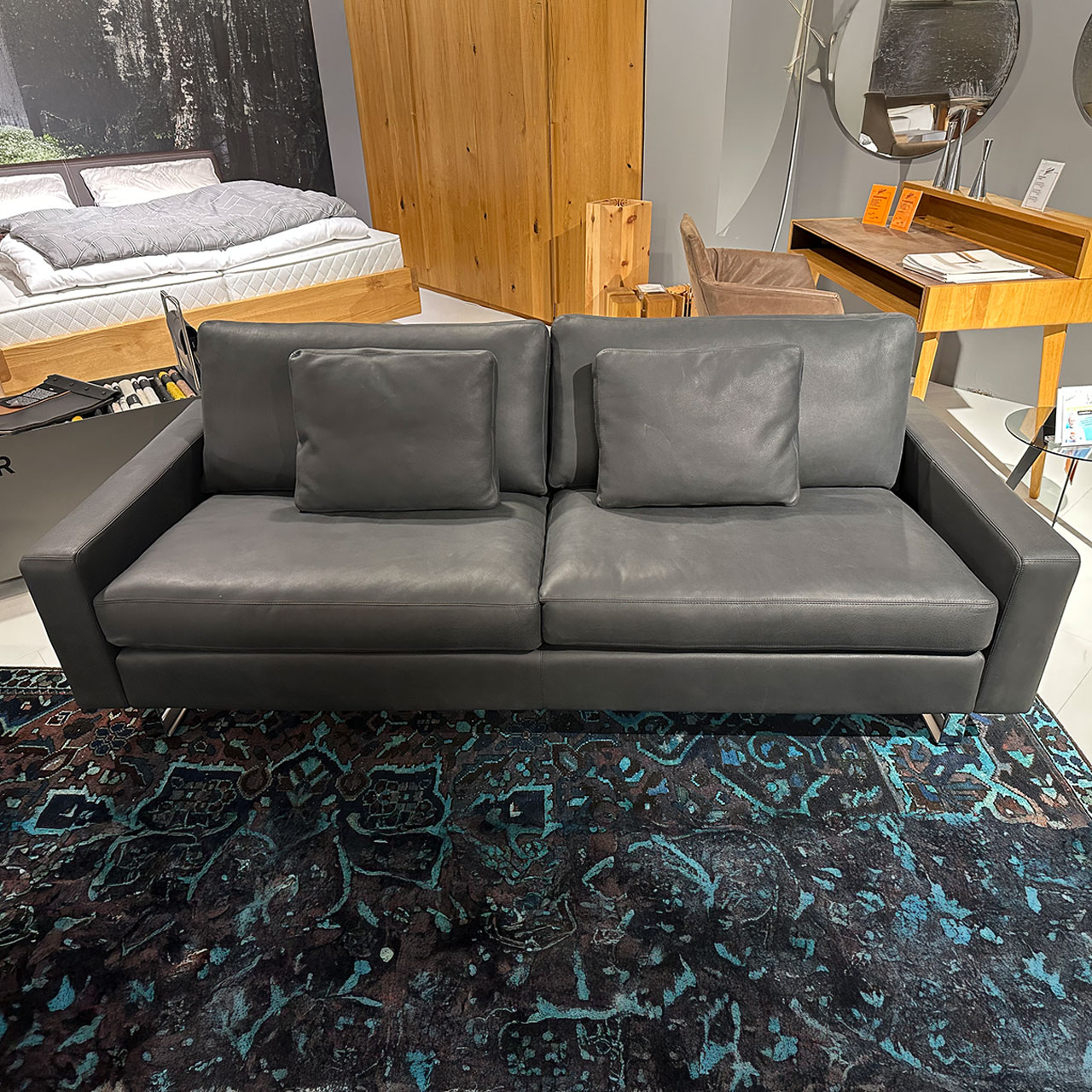 Zweisitzer-Sofa aus schwarzem Leder mit zwei passenden Kissen.