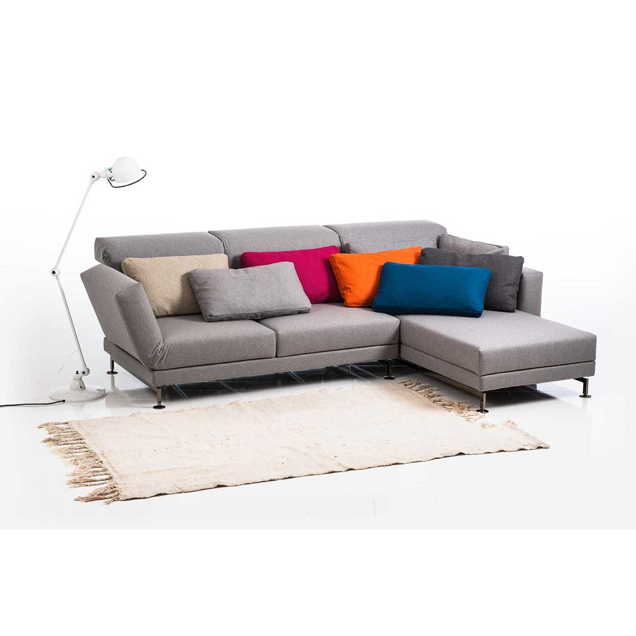 Eckgarnitur in grauem Stoff mit Longchair rechts, dekoriert mit sieben Kissen.