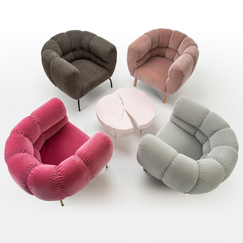 Sicht von schräg oben auf vier Sessel, die kreisförmig um einen Beistelltisch angeordnet stehen. Die Sessel sind haben eine auffällig opulente, halbrunde Rückenlehne, welche die gesamte Sitzbasis umschließt.