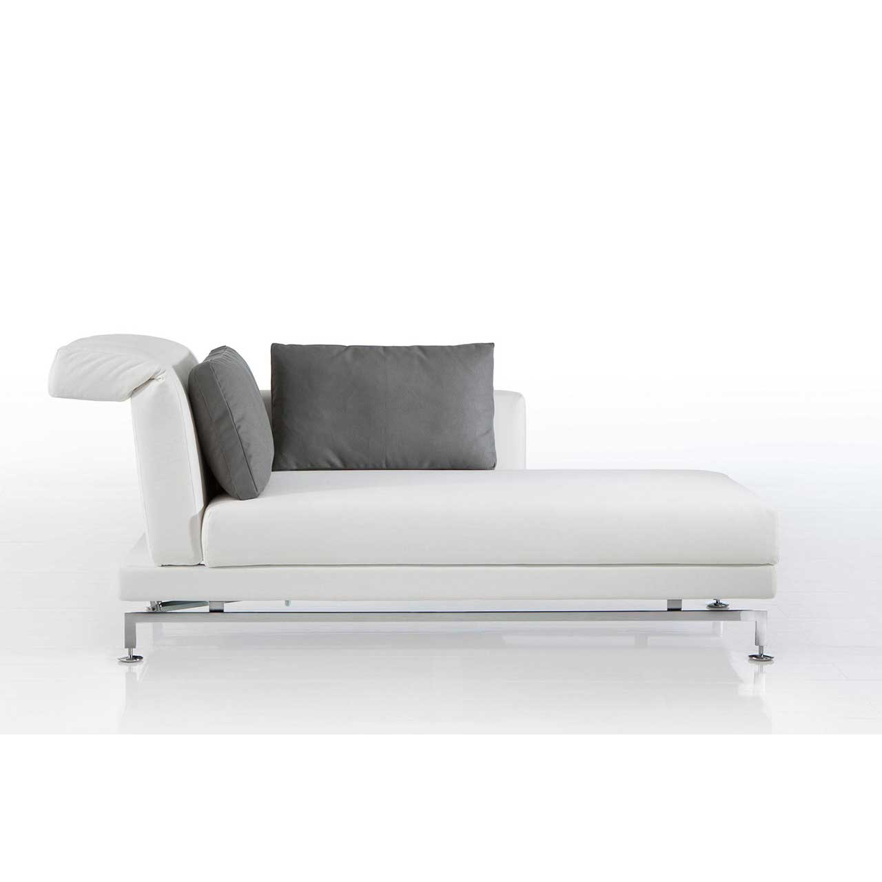 Longchair mit Kufen in chrom glänzendem Metall und mit weißem Leder bezogen. Auf dem Longchair liegen zwei Kissen mit grauem Bezug.
