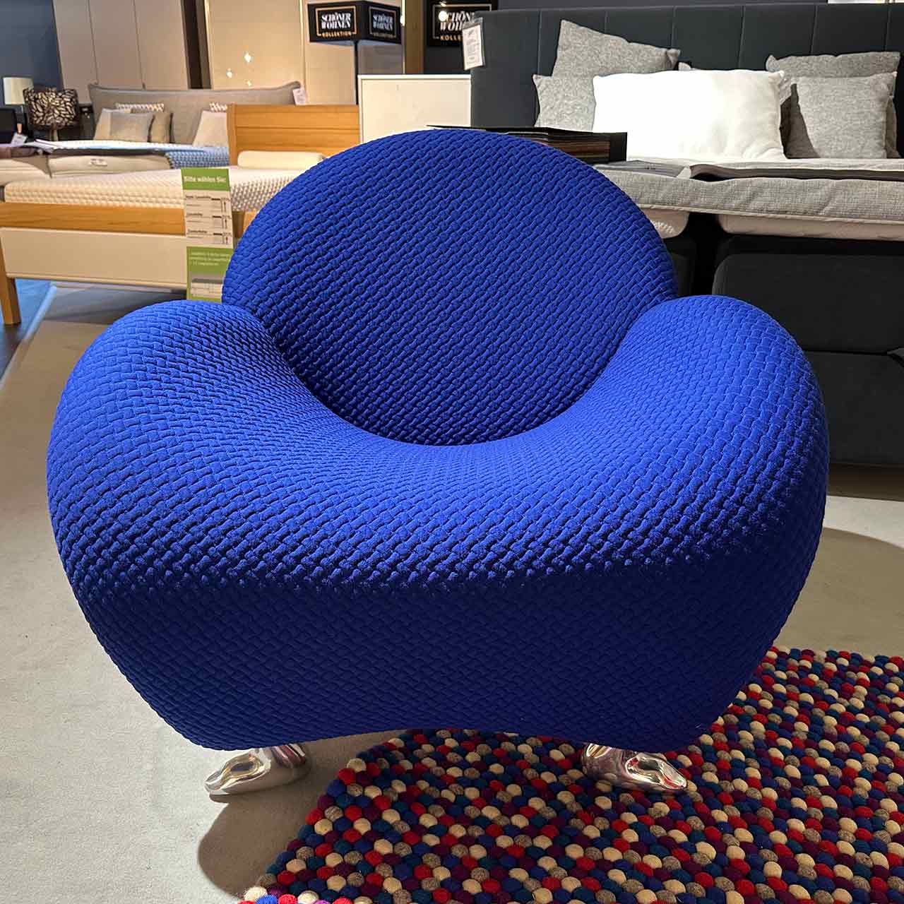 In der Frontalaufnahme sieht der Sessel rund aus wie ein Raumschiff. Unten sind chromfarbene Tierfüße sichtbar.