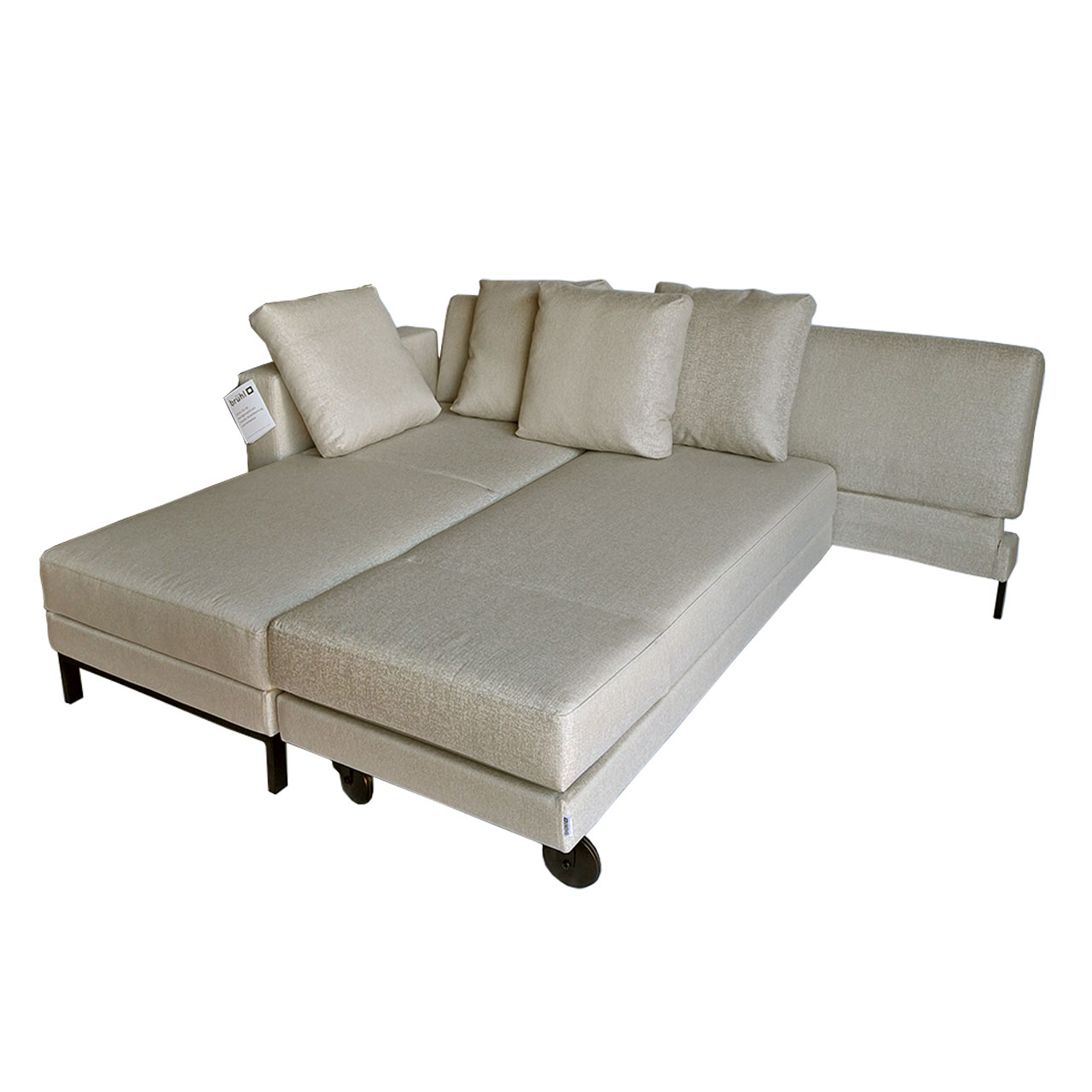 Beiges mit Stoff bezogenes Ecksofa mit Recamiere links und Drehsofa rechts, umgebaut zu einer Schlaf- und Liegefläche.