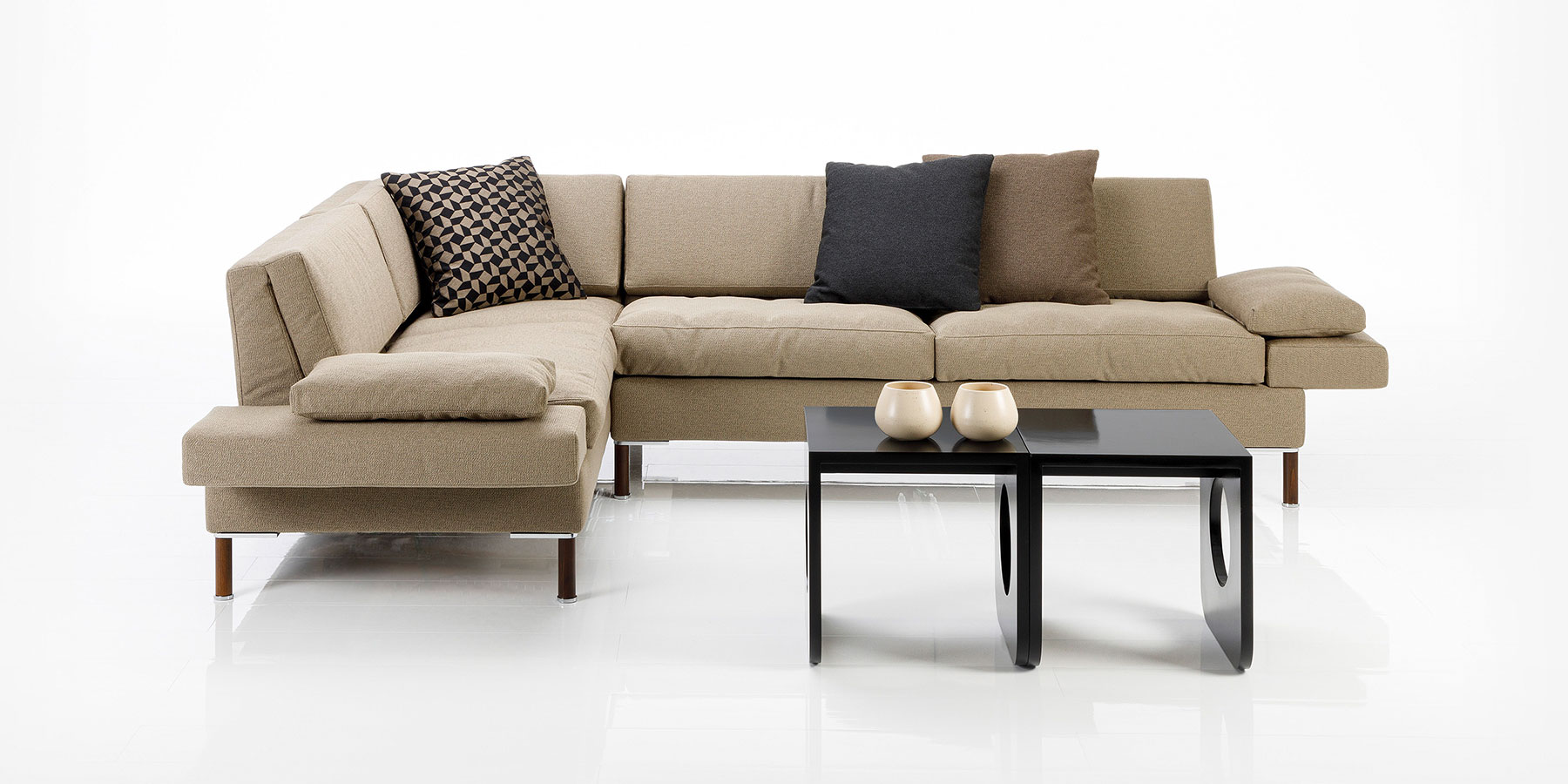 Eckgarnitur in beigem Stoff. Mit Decokissen in schwarzem Stoff.