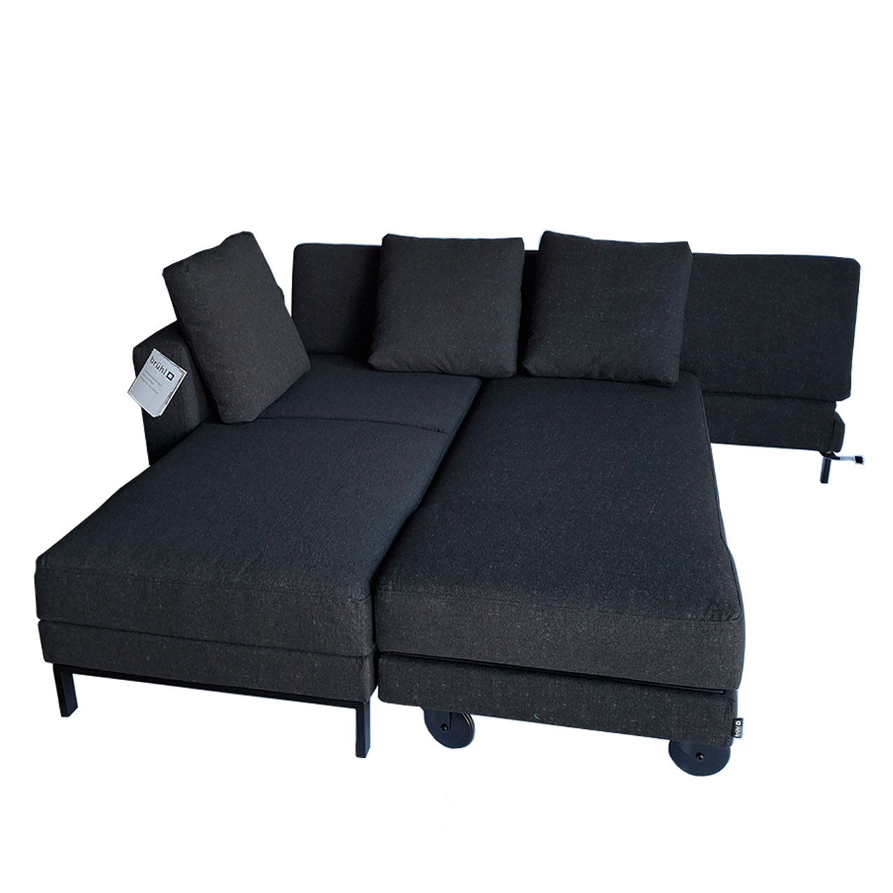 Schwarzes mit Stoff bezogenes Ecksofa mit Recamiere links und Drehsofa rechts, umgebaut zu einer Schlaf- und Liegefläche.