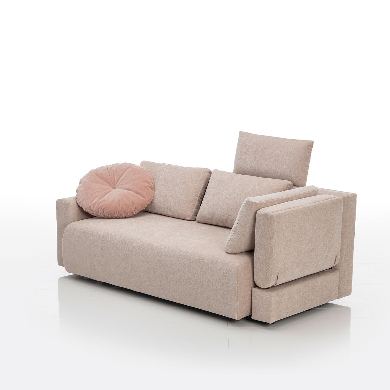 Bodennahes beiges Sofa mit drei eckigen und einem runden Kissen. Die rechte Armlehne ist abklappbar.