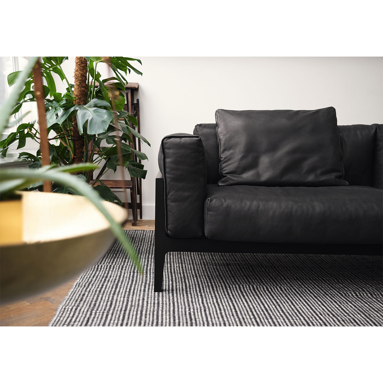 Detailaufnahme der Hälfte eines Elm-Sofas mit dunklem Lederbezog