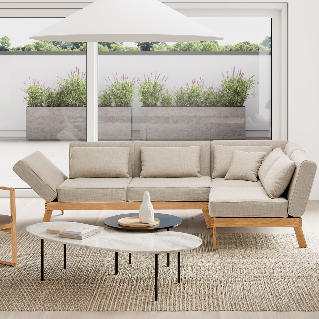 Ambientebild. Eine Eckgarnitur der Serie brühl lofoten lounge steht vor einem bodentiefen Fenster. Der Blick geht auf eine Terrasse.