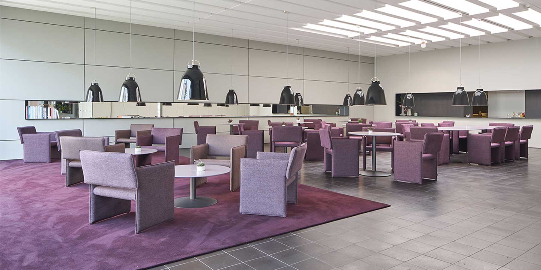 Viele COR Noto Sessel und Stühle gruppiert um runde Tische in einer Bistro-Atmosphäre