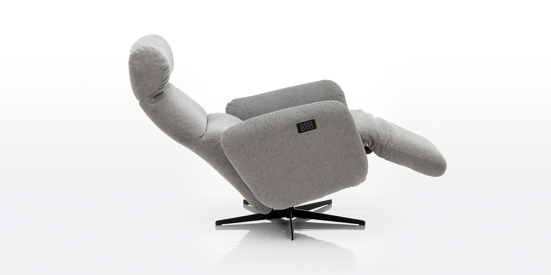 Elektrischer Relaxsessel mit Drehbasis in hellgrauem Stoff. Der Sessel ist in Liegeposition abgesenkt.