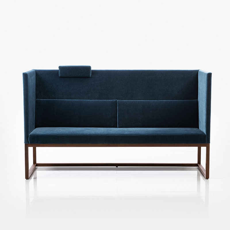 Eine Bank mit hohen Rücken- und Armlehnen in einem dunkelbauen Stoff. Das Untergestell ist in dunklem Holz.