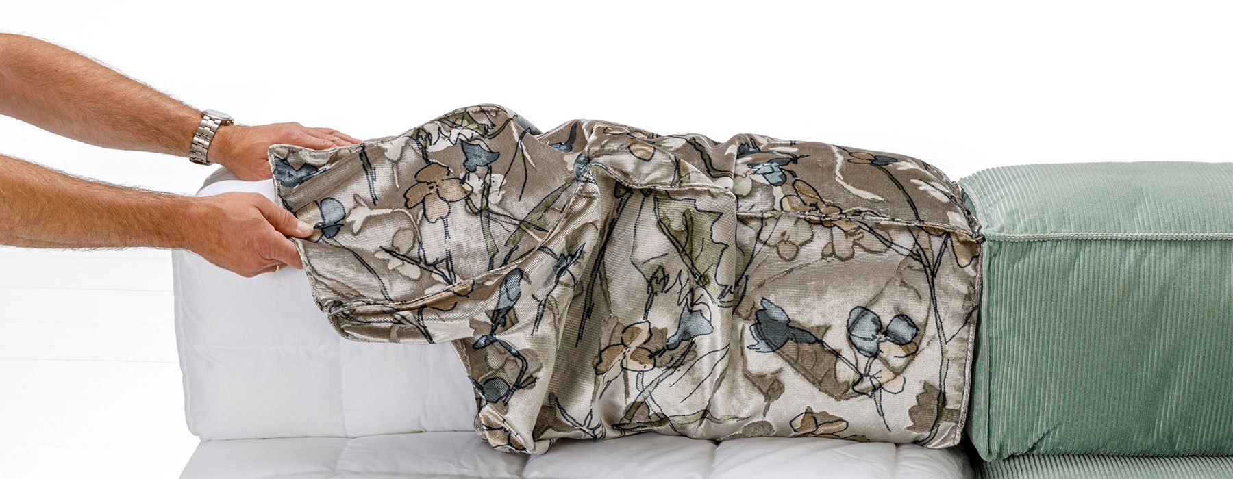 Zwei Männerhände beziehen ein  kubisch geformtes Rückenpolster mit einem neuen Bezug.