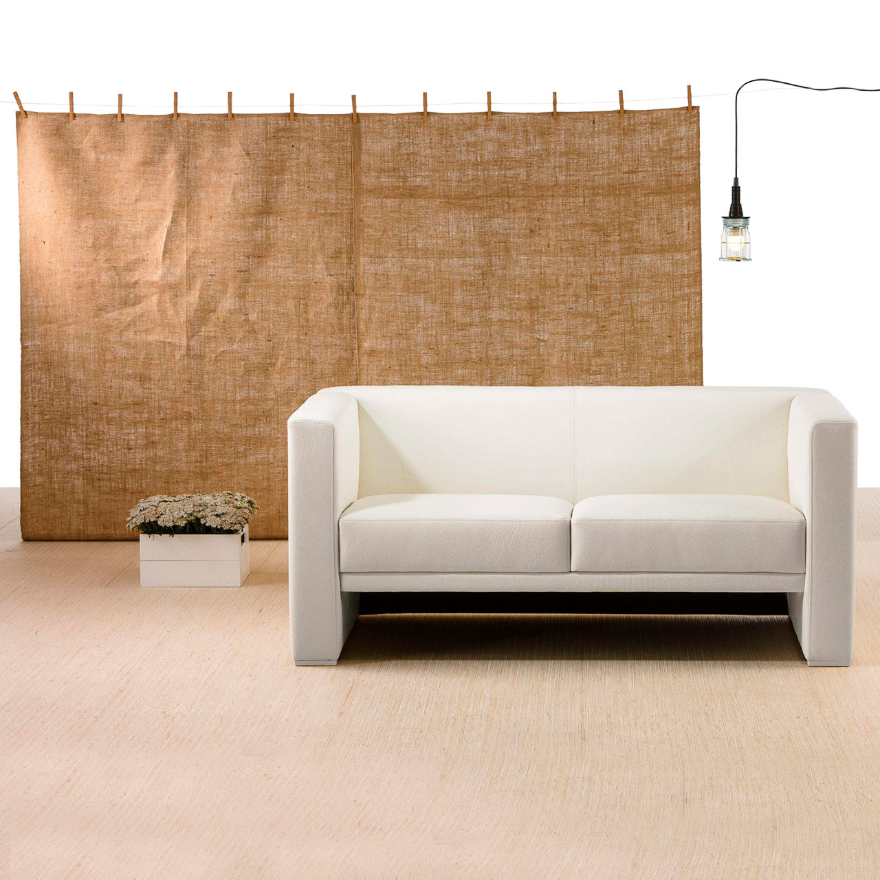 Weißes Ledersofa vor einem Raumteiler in groben Leinenstoff.