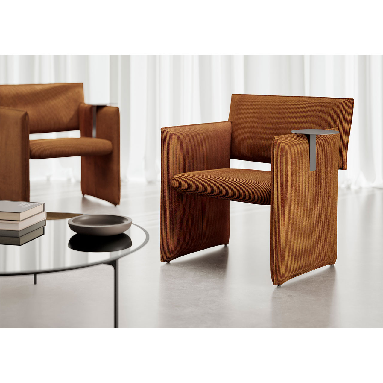 Auf die rechte Armlehne des Noto Sessels ist ein runder Aufstecktisch mit einer Edelstahl-Oberfläche aufgesteckt.