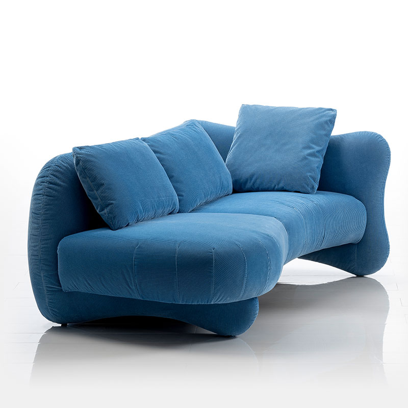 Ein blaues Sofa mit geschwungenen Formen. Rechts offen ohne Armlehne.