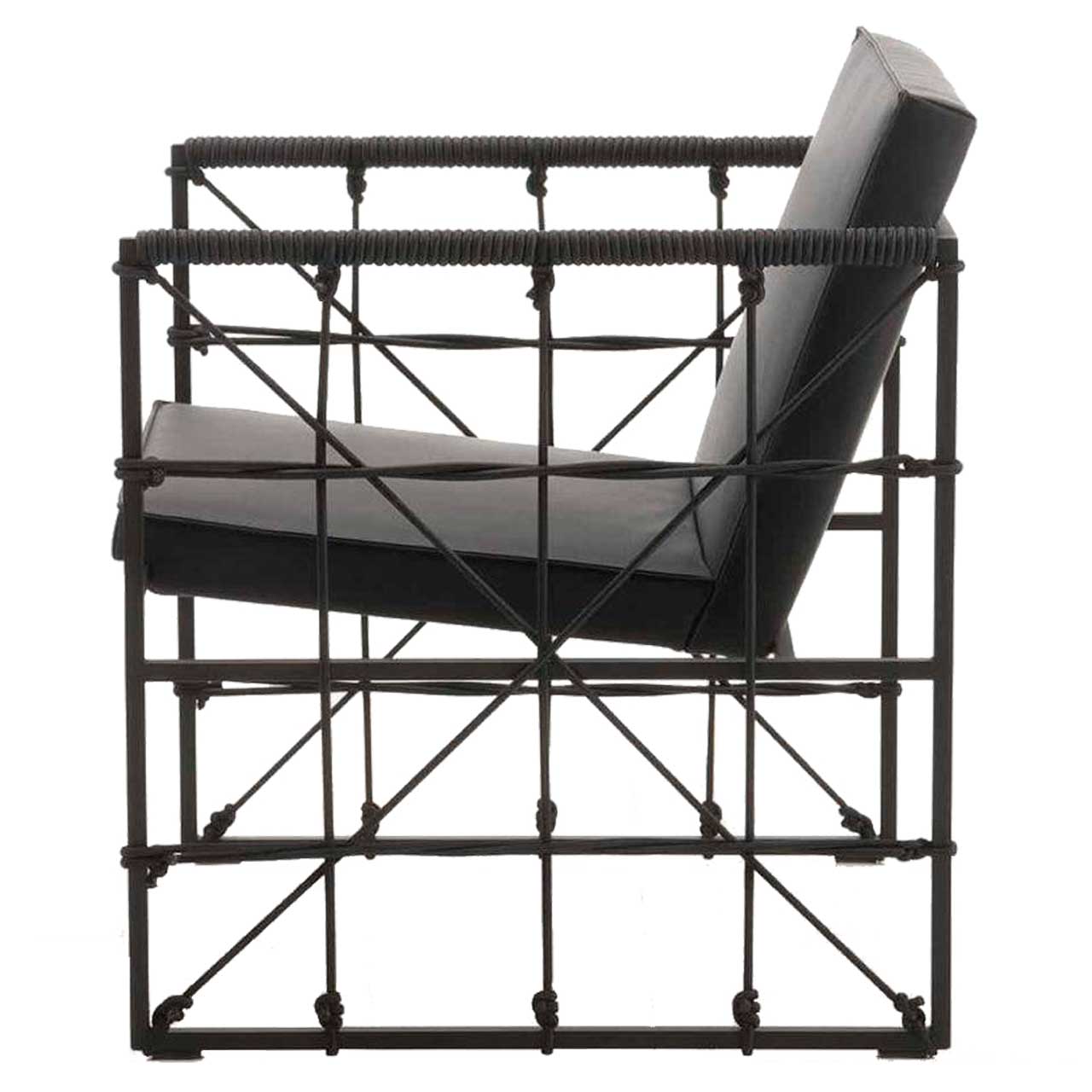 Filigraner Sessel mit schwarzem Untergestell und mit schwarzem Leder bezogen. Die Seiten sind mit schwarzem Bungeeseilen bespannt. 