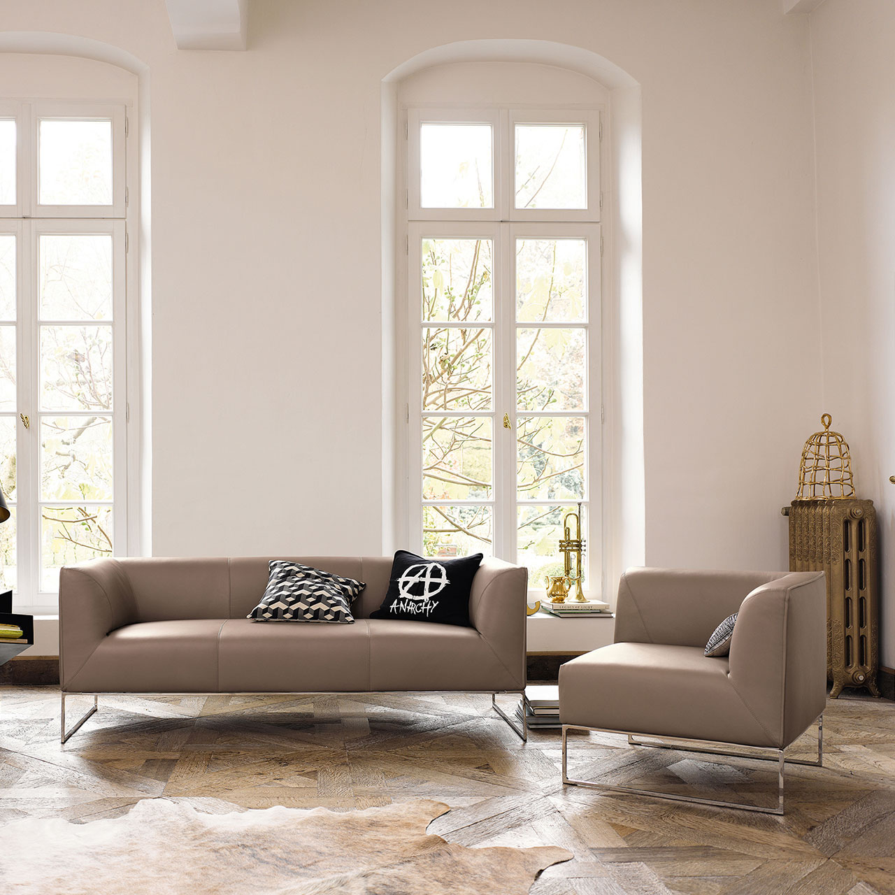 Sofa und Ecksessel in passendem Bezug mit Chromkufen in einem Wohnzimmer auf Parkettboden mit Kissendekoration