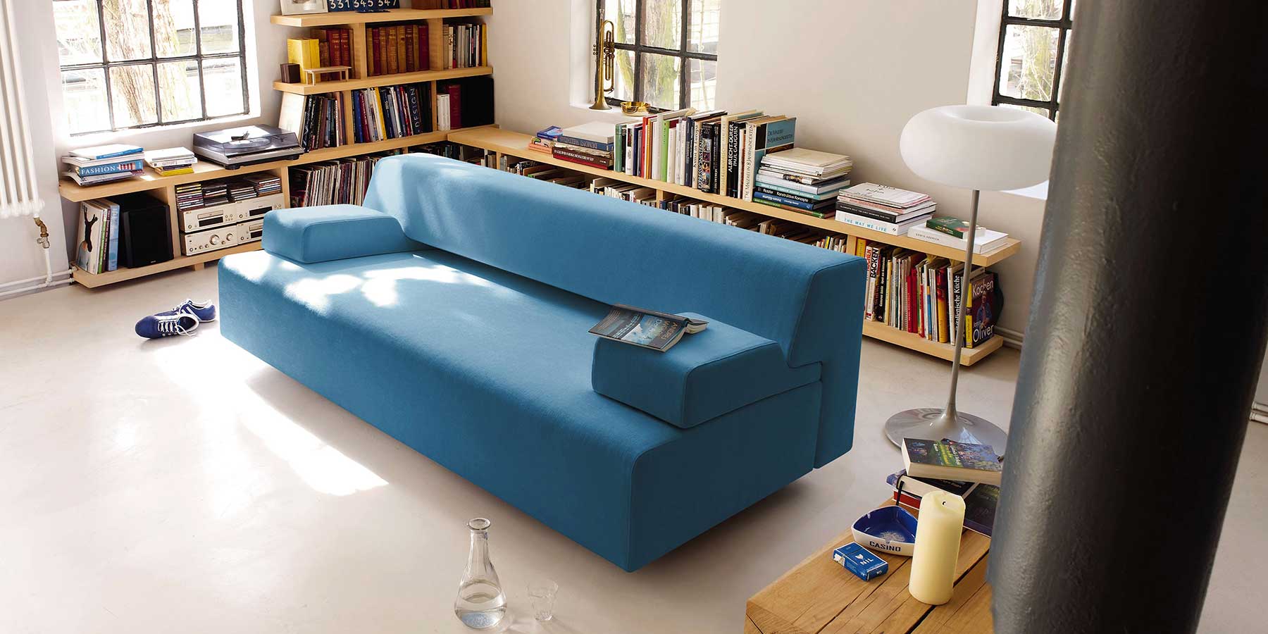 Blaues Schlafsofa mit zwei aufgelegten Armlehnen im Wohnzimmer