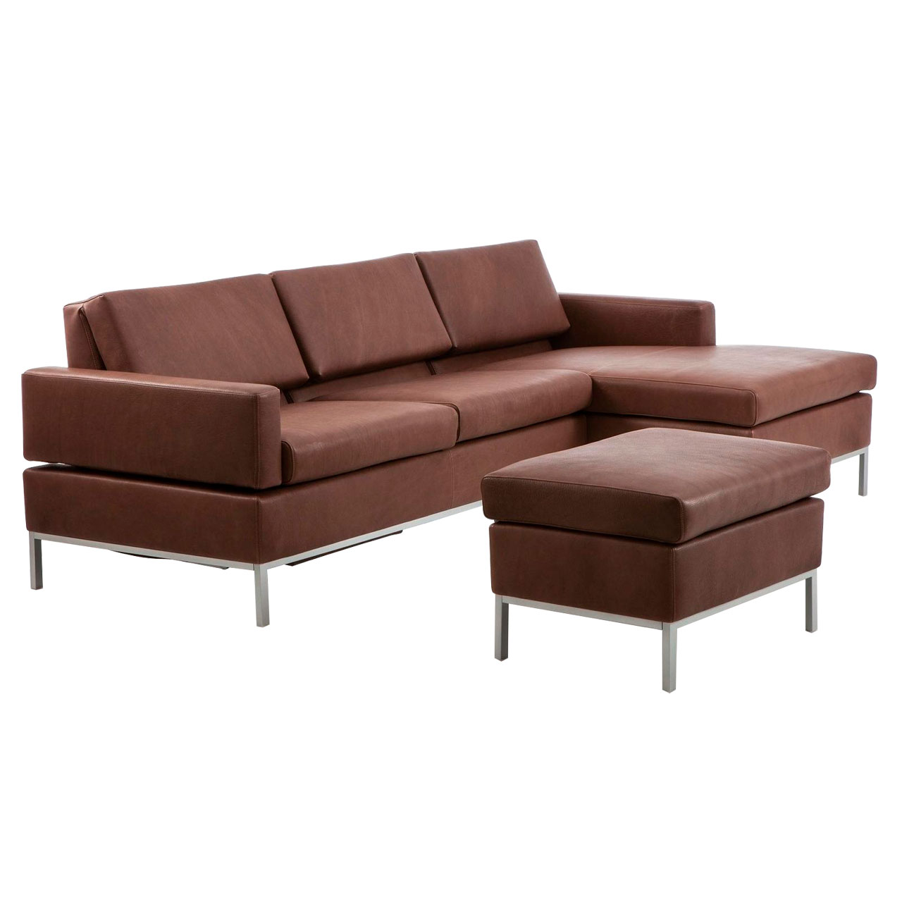 Leicht schräge Sicht auf eine dunkelbraune Ledergarnitur mit Longchair rechts und Anstellsofa links. Vor der Garnitur steht ein Hocker.