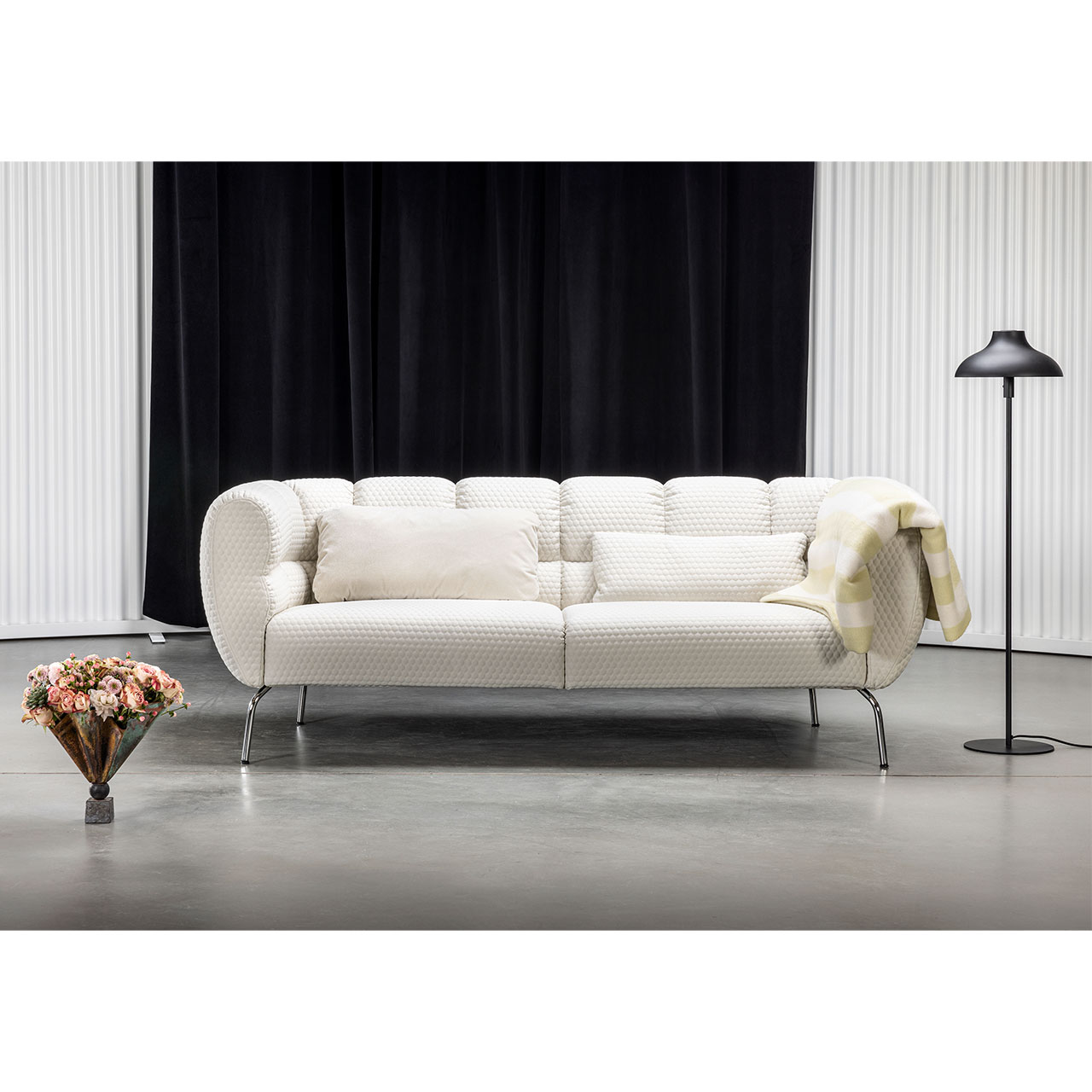 Sofa der Serie brühl magnolia in cremeweißen Stoff mit chrom glänzenden Metallfüßen.