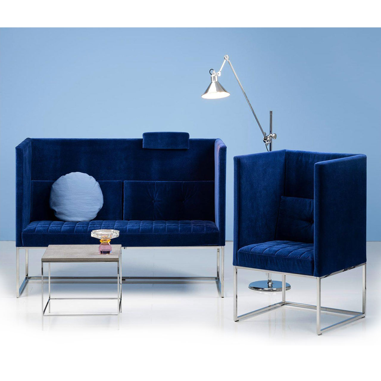 Ambientebild: Eine blaue Polsterbank mit passendem Sessel stehen vor einer hellblauen Wand. Die Seiten und Rücken der Möbel sind hoch.
