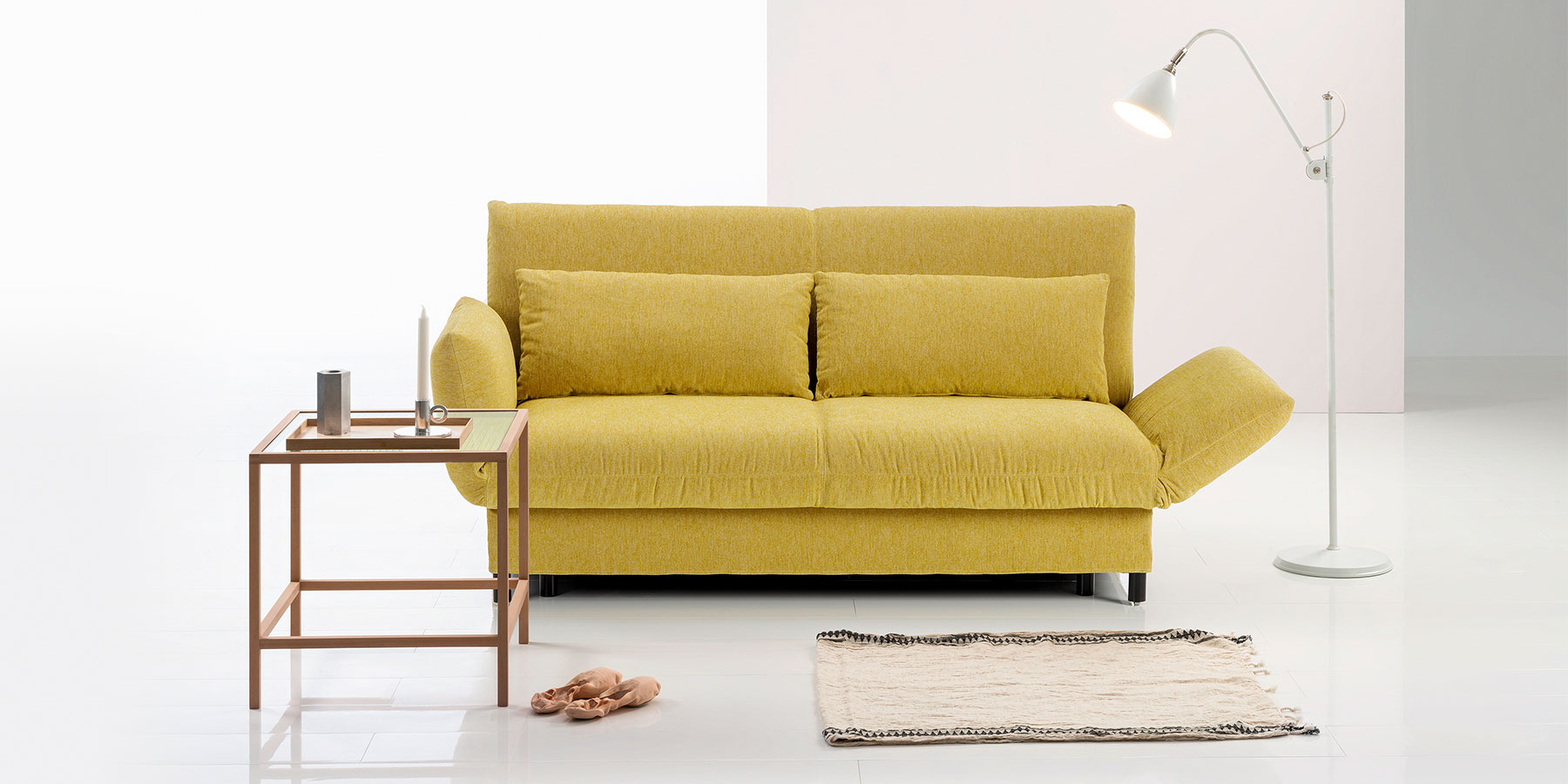 Ein senfgelbes Sofa mit rechts halb abgesenkter Armlehne.