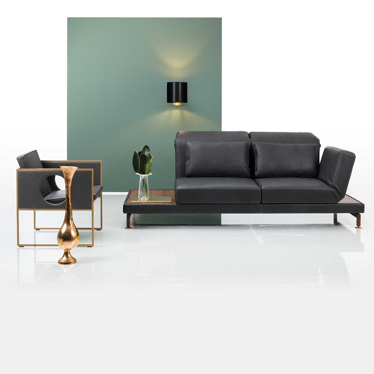 Ambientebild: Anstellsofa in schwarzem Leder mit Armlehne links und Abstellflächen rechts und rechts. Links des Sofas steht ein Sessel der Serie grace.