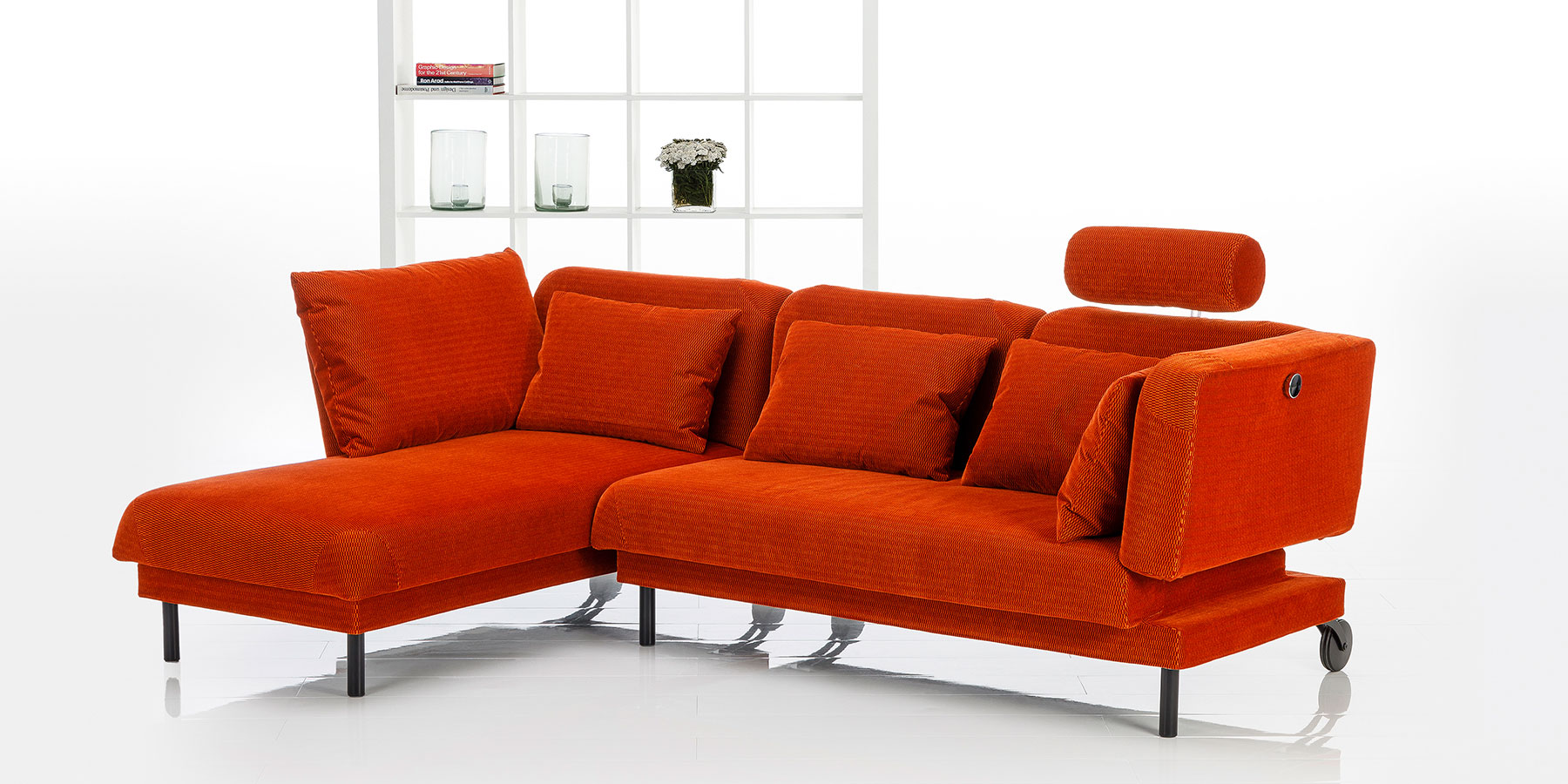 Ein rotes Ecksofa mit aufgesetzter Kopfstütze rechts.