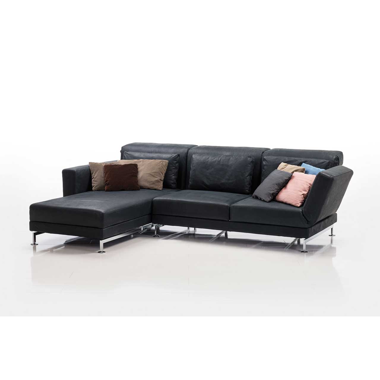 Eckgarnitur von brühl moule small in schwarzem Leder mit Longchair links, dekoriert mit sehr vielen bunten Kissen.