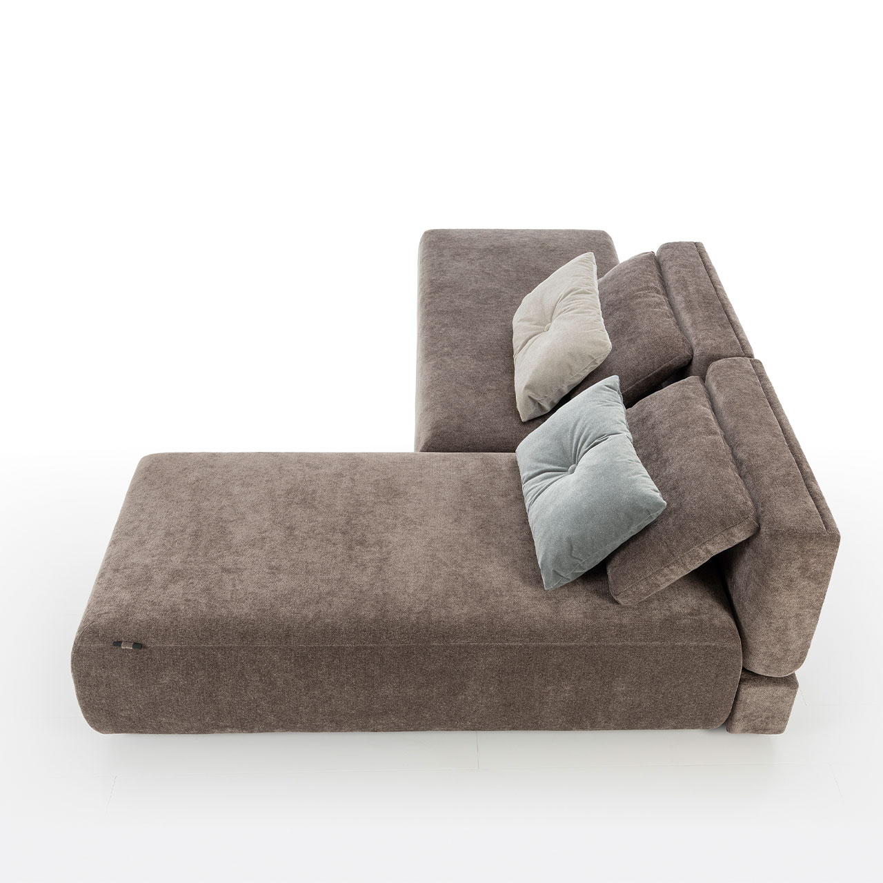 Bodennahes braunes Eckofa mit Drehsofa links und Longchair rechts. Auf dem Sofa liegen zwei eckige Kissen.